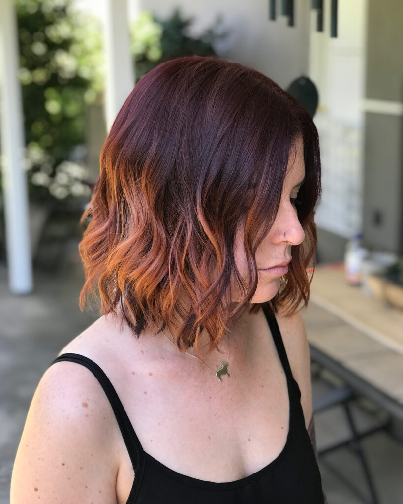 Wavy auburn bob with warm copper highlights and soft layered texture.