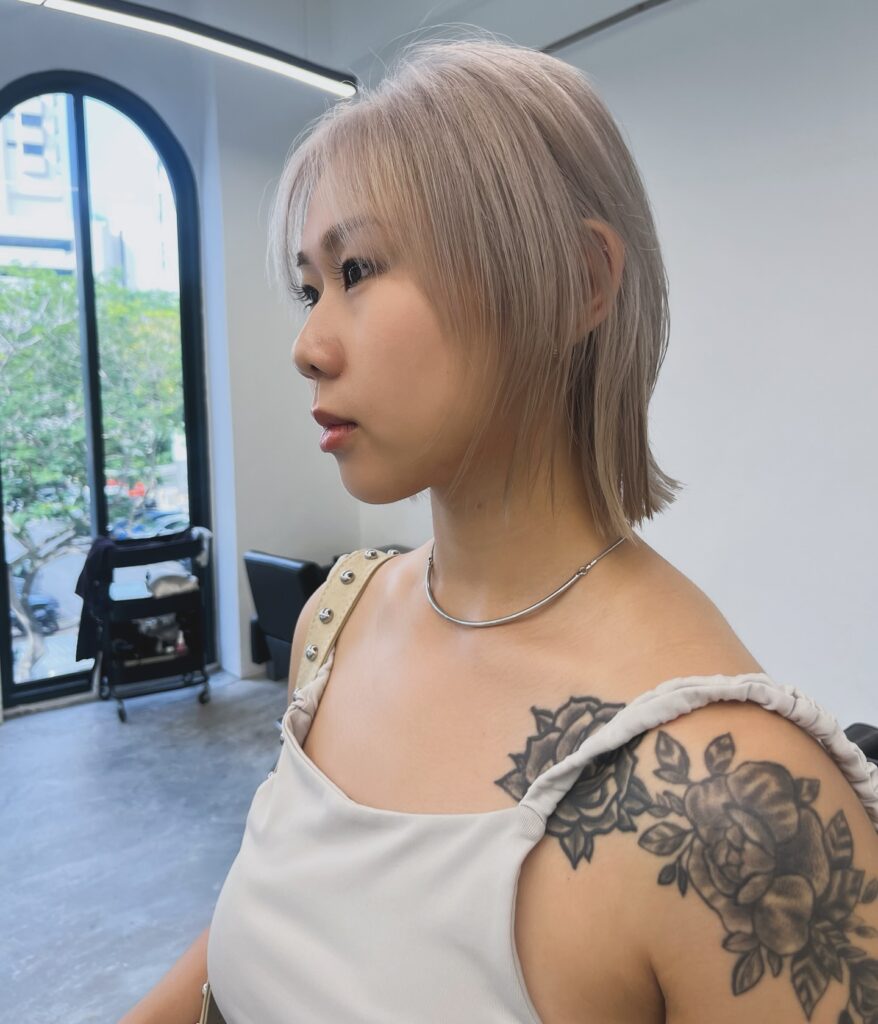 Short wispy ash blonde layered bob with soft face framing pieces and a sleek lightweight finish.