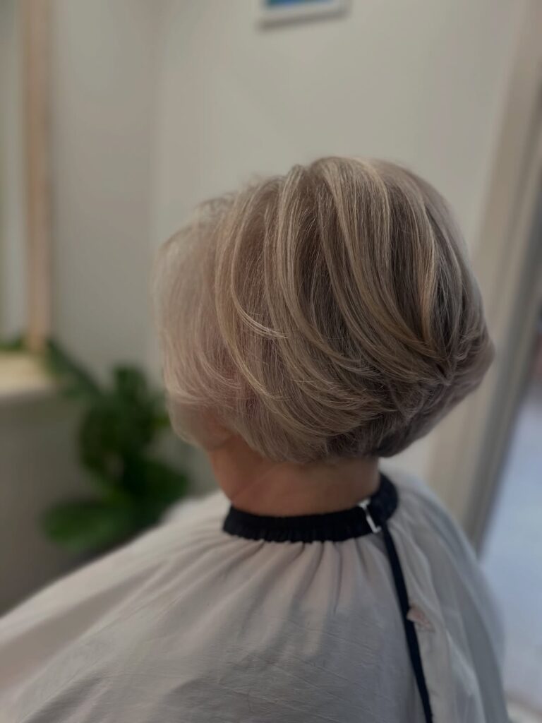 Rounded ash blonde layered bob with feathered volume and soft, smooth texture.