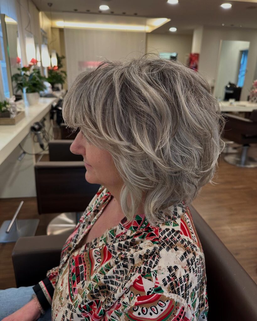 Wavy layered ash blonde shag bob with soft texture and feathered volume throughout.