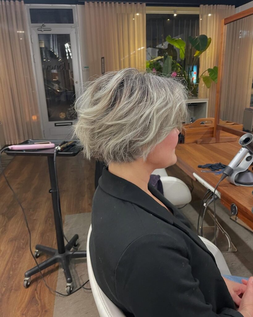 Textured ash blonde bob with tousled layers, darker roots, and soft voluminous waves.