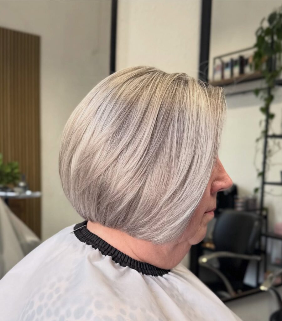 Sleek silver ash blonde bob with smooth layers and softly stacked volume.