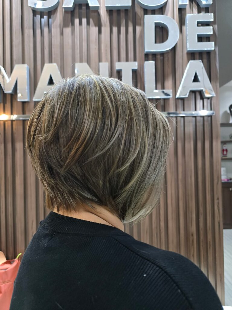 Angled ash blonde stacked bob with layered volume and sleek front sections.