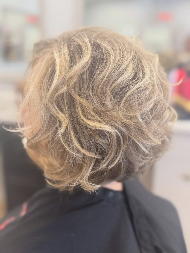 A tousled champagne blonde layered bob with soft waves and voluminous texture throughout the crown.