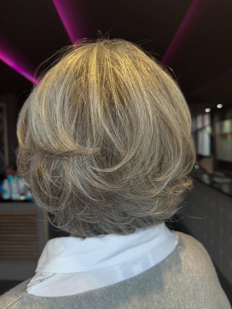 Feathered beige blonde bob with rounded layers and soft volume through the back and sides.