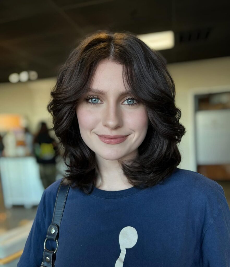 Dark brunette layered bob with curtain bangs and softly curled voluminous ends.