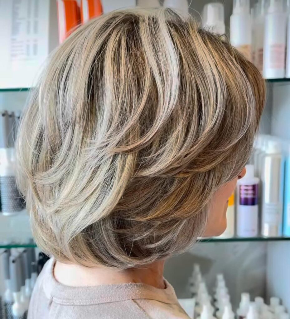 Creamy blonde layered bob with rounded stacked layers and soft voluminous shape.