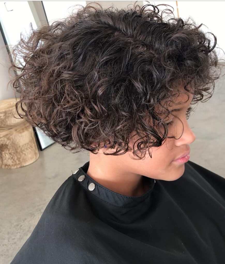 A curly espresso-brown layered bob with defined curls and rounded volume.