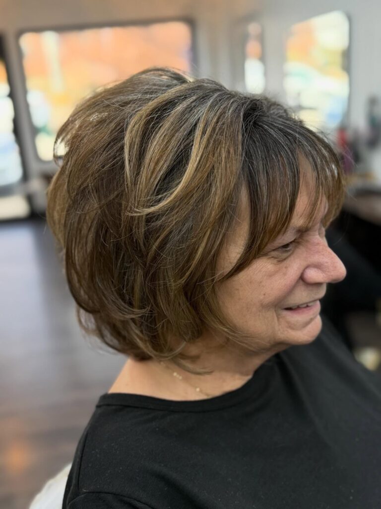 Honey brunette layered bob with golden highlights and rounded volume through the crown.