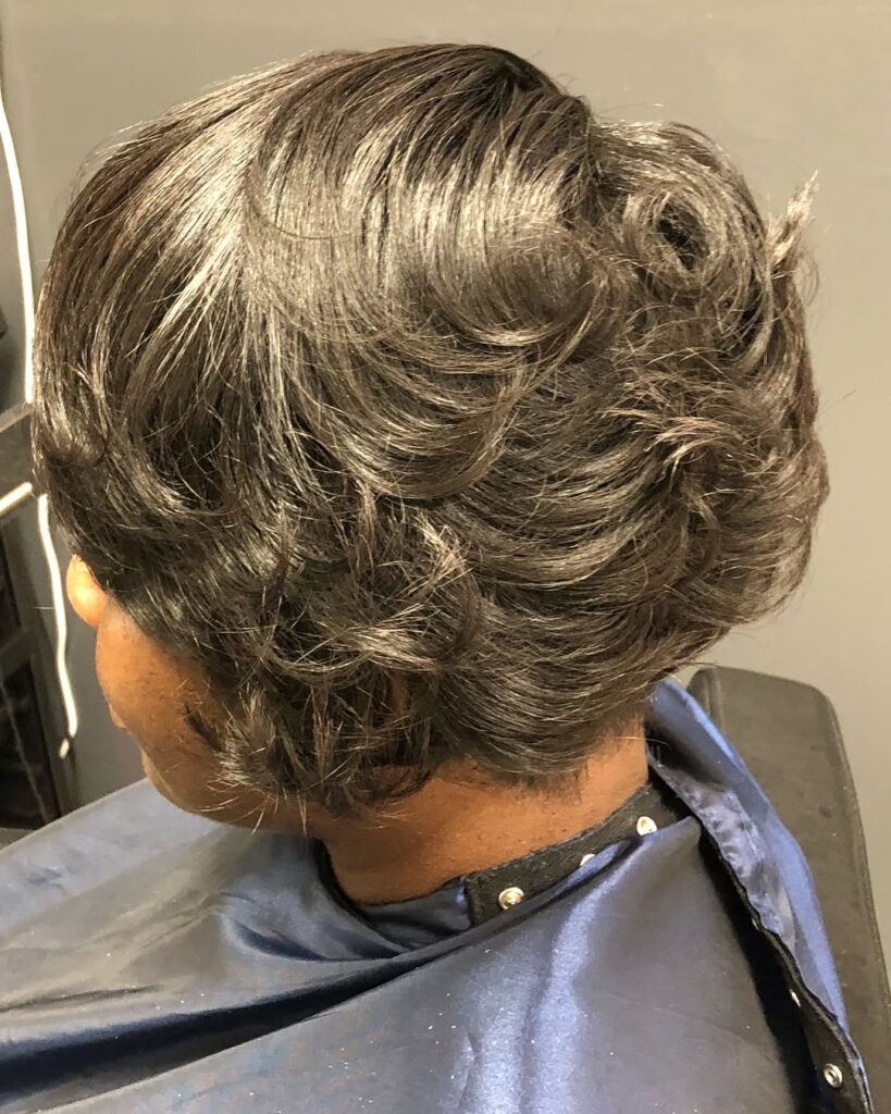 Sculpted brunette layered bob with curled stacked layers and soft crown volume.