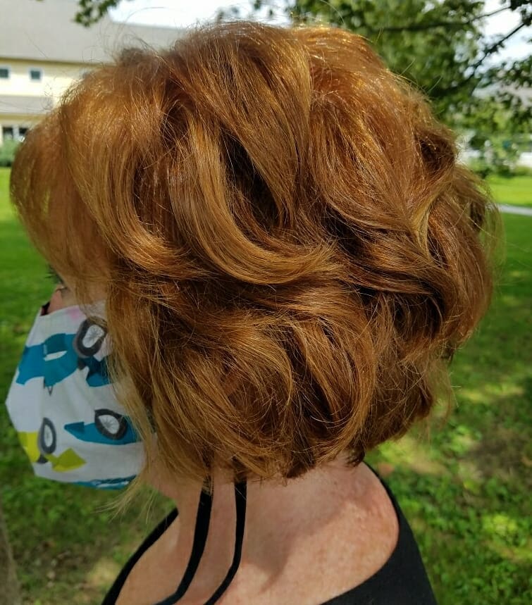 A voluminous ginger layered bob with fluffy feathered layers and side-swept volume.