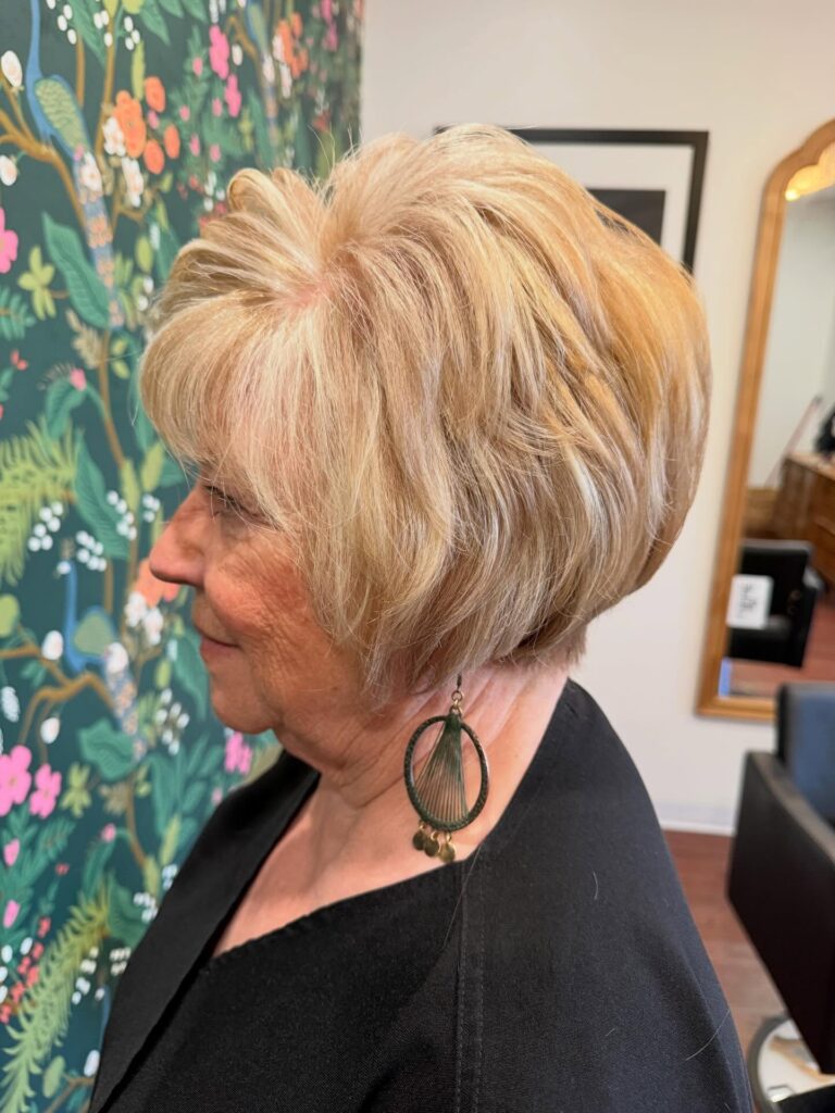 Rounded honey blonde layered bob with stacked volume and soft feathered ends.