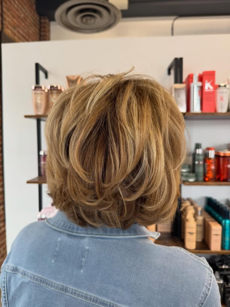 Rounded golden blonde layered bob with feathered ends and a full voluminous shape.
