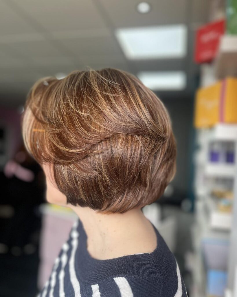 Polished cinnamon brown layered bob with soft stacked layers and rounded volume.