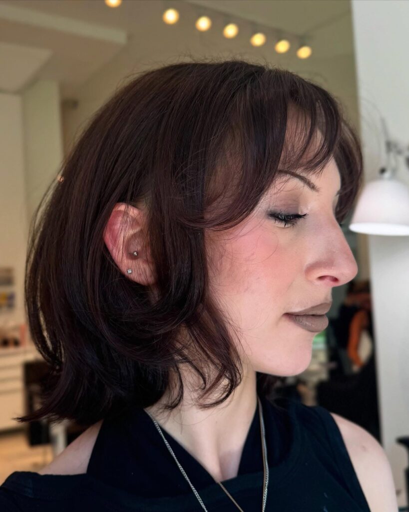 Soft wavy brunette bob with curtain bangs and layered textured ends.