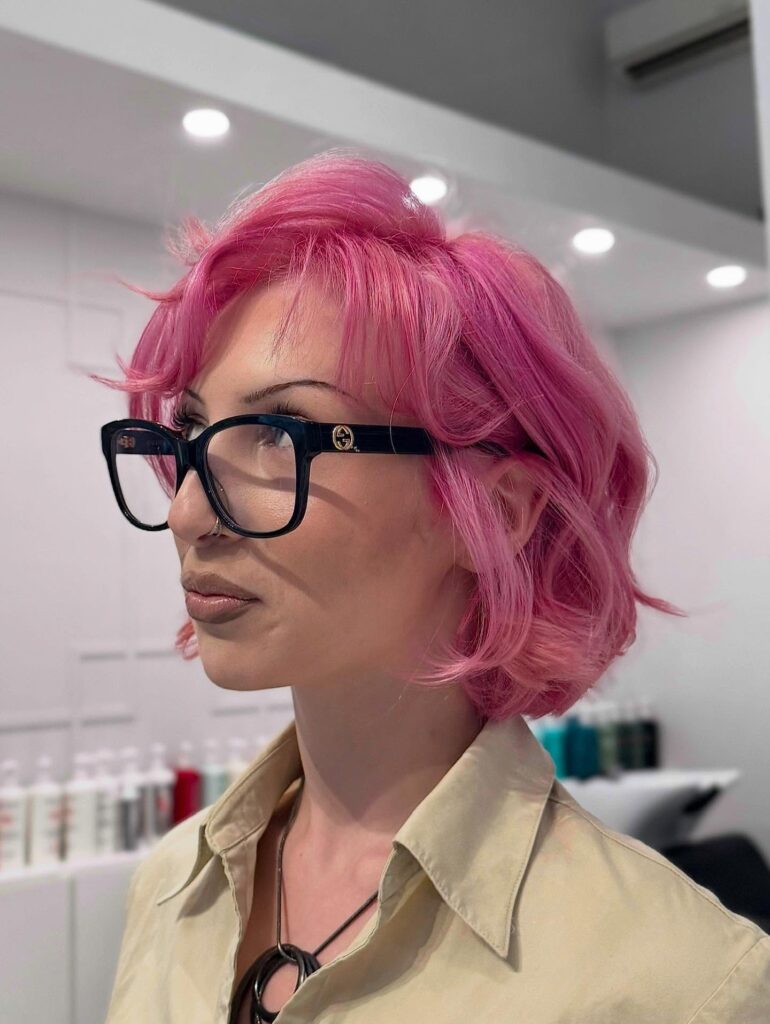 Bright pink layered bob with curled fringe and soft wavy texture.