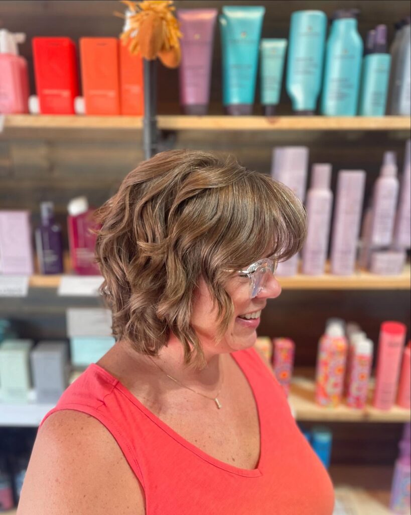 Wavy layered brunette bob with soft side fringe and loose textured curls.