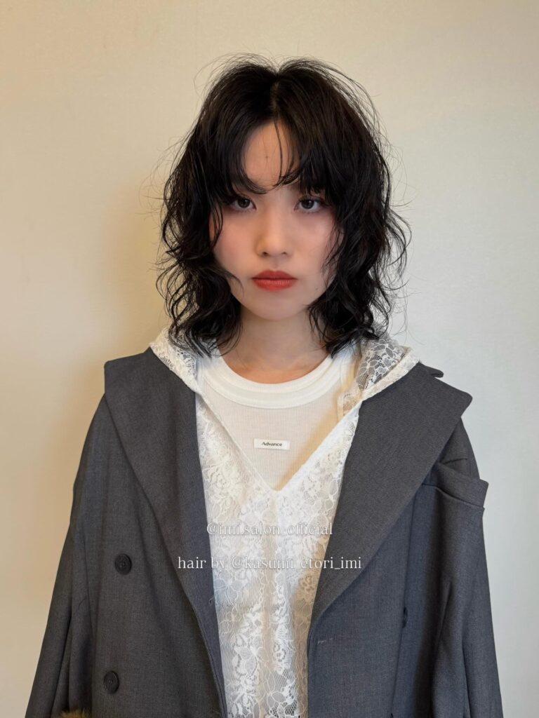 Dark curly shag bob with wispy fringe and soft layered texture.