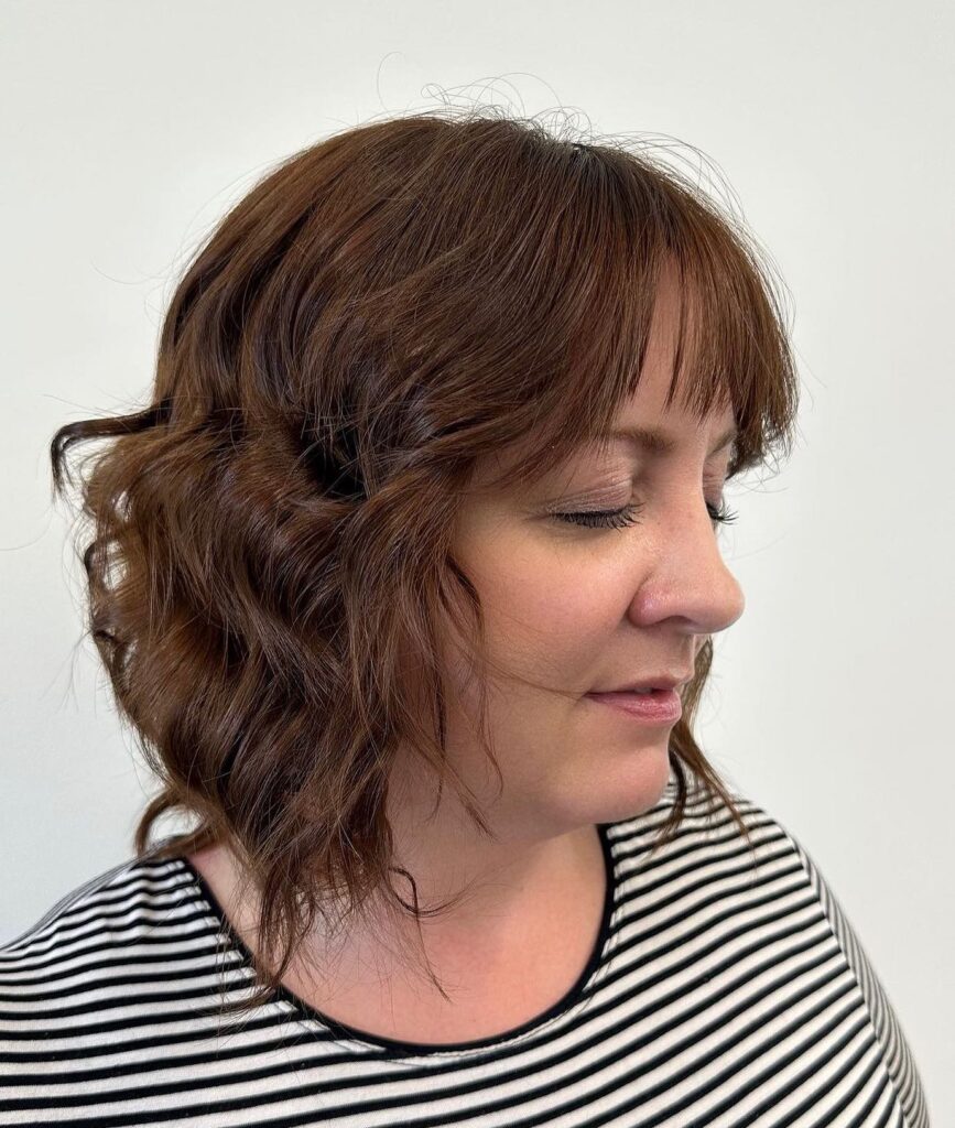 Chestnut brown wavy layered bob with thin fringe and tousled texture.