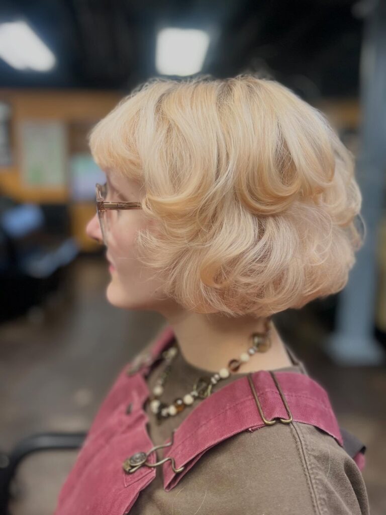 A creamy blonde feathered bob with fluffy layered volume and softly curled ends.