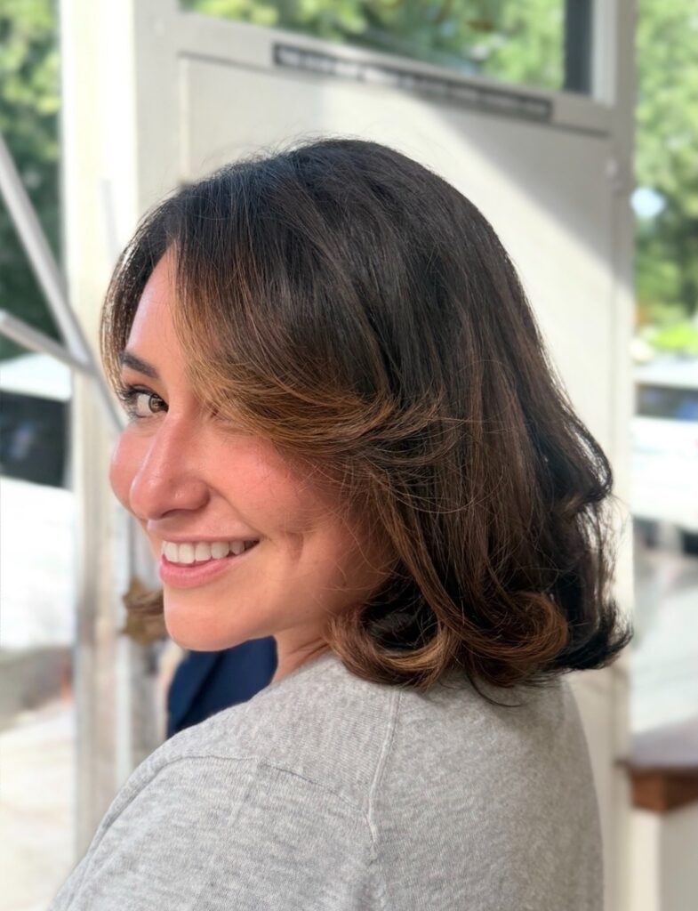 Layered brunette bob with curled ends and soft caramel highlights around the face.
