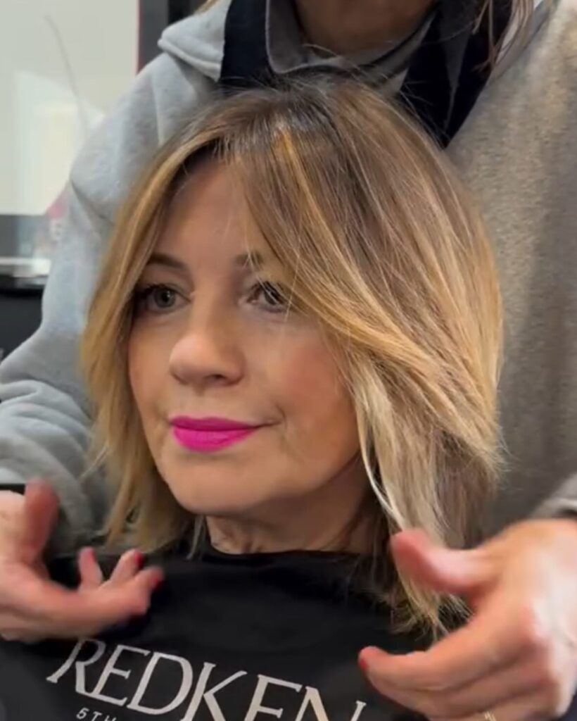 Blonde layered lob with soft face framing highlights and smooth textured layers.