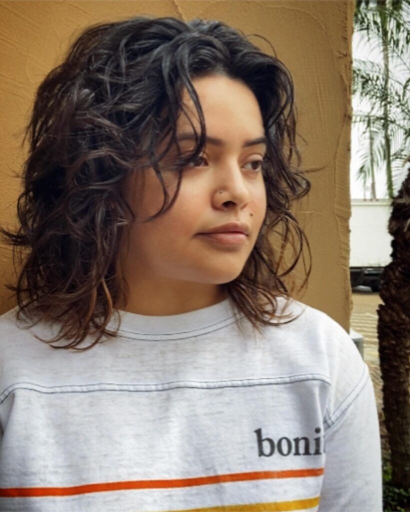 Shoulder-length layered curly bob with tousled soft coils and face-framing pieces.
