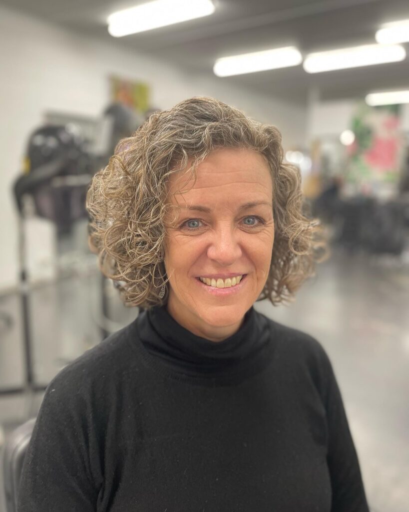 Short layered curly bob with soft silver coils and a rounded voluminous shape.
