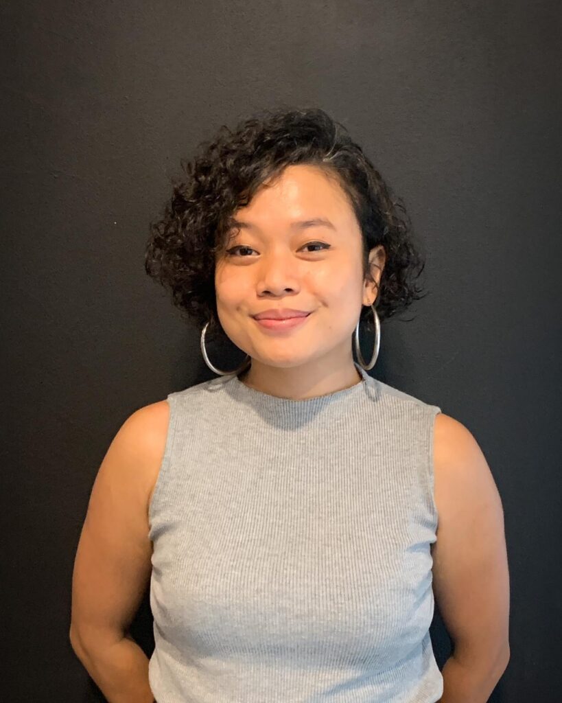 Short side-swept curly bob with soft layered texture and dark natural curls.