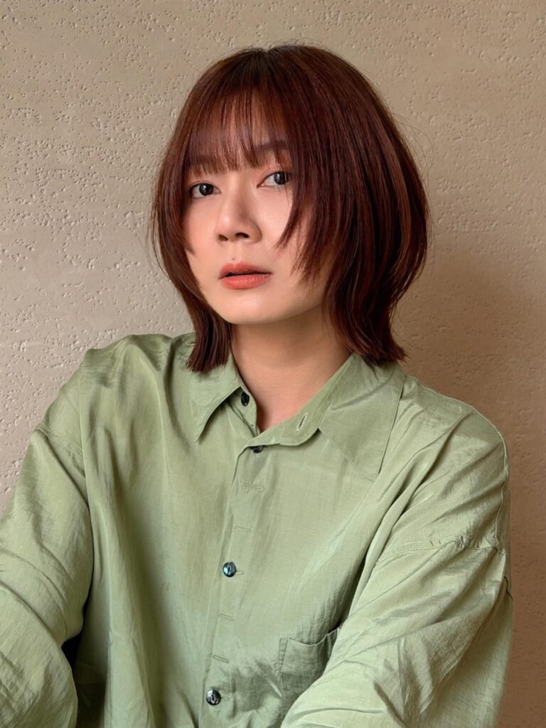 Chestnut brown textured bob with wispy bangs and sleek layered ends.