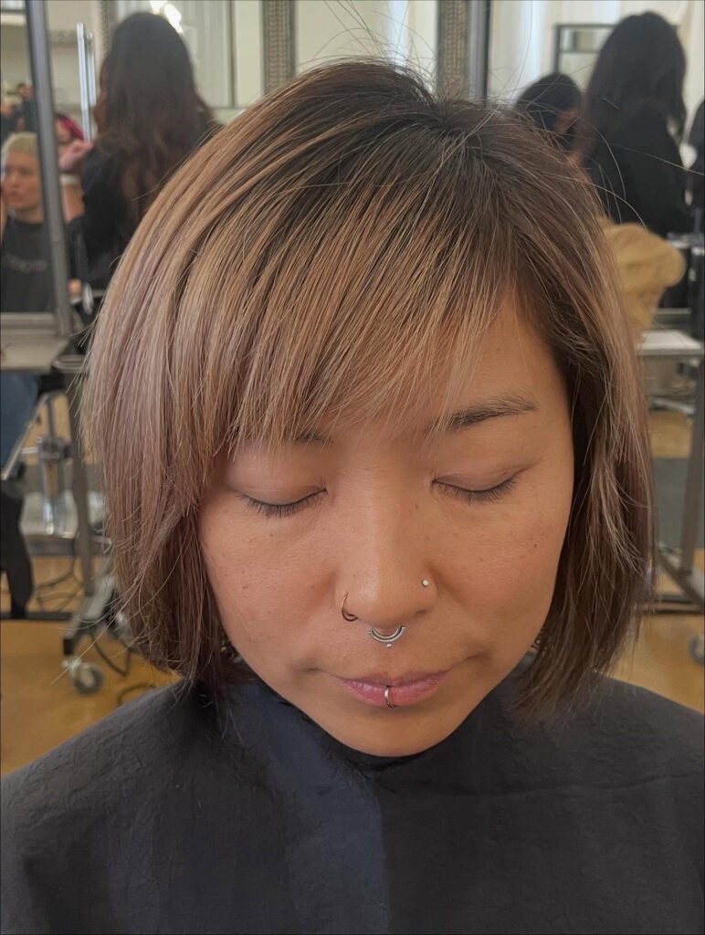 Short layered brunette bob with side-swept bangs and lightly choppy ends.