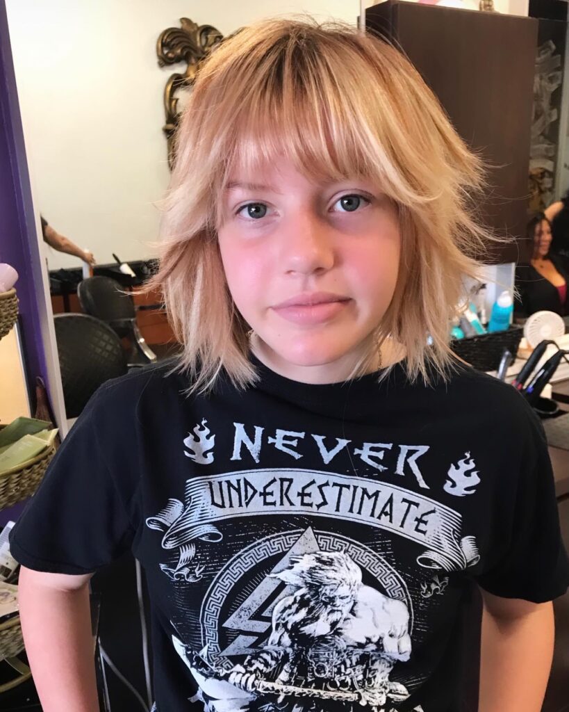 Shaggy blonde layered bob with wispy bangs and textured ends.