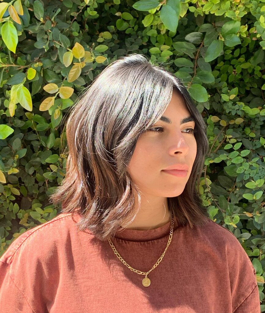 Wavy brunette lob with curtain layers and soft face framing texture.