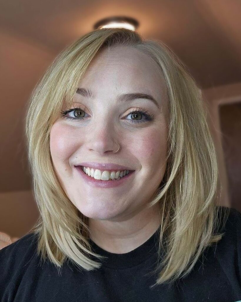 Soft blonde layered bob with a side part and smooth face-framing pieces.