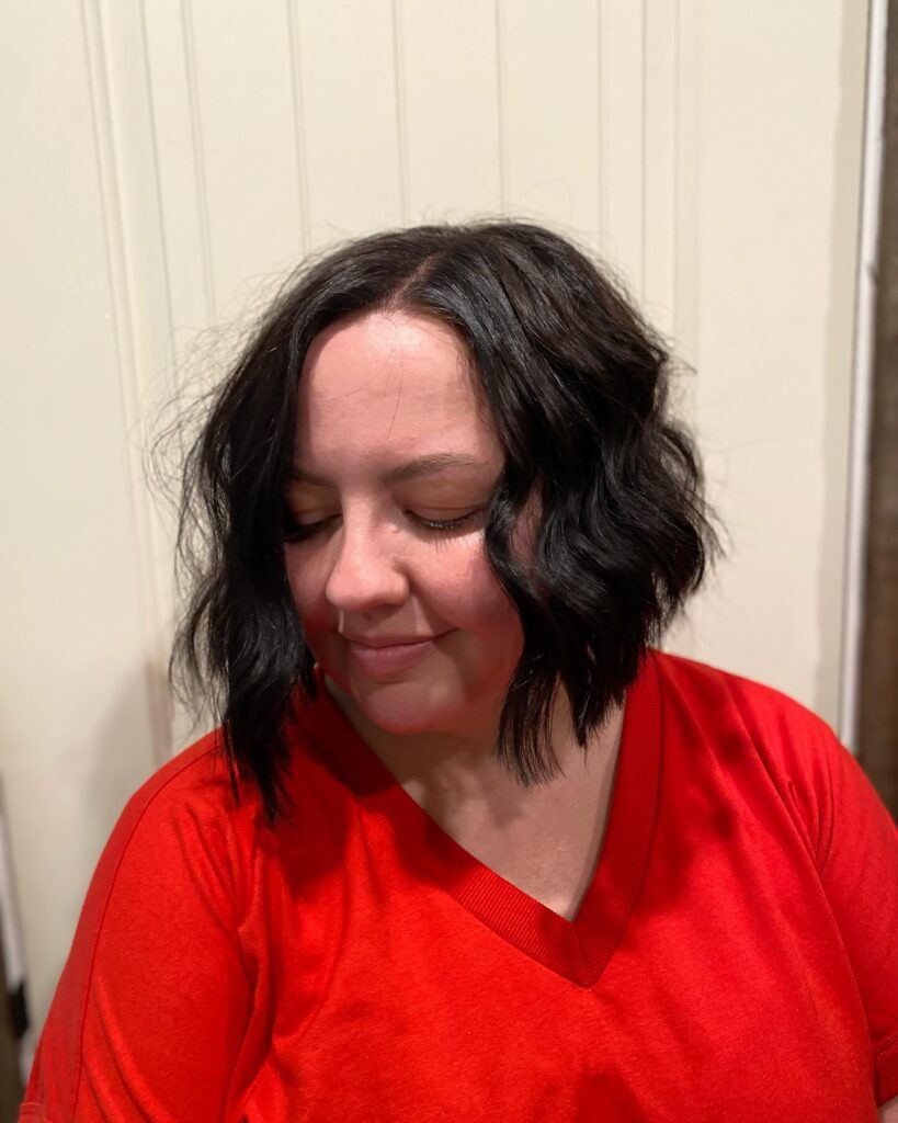Black wavy layered bob with a center part and textured ends.