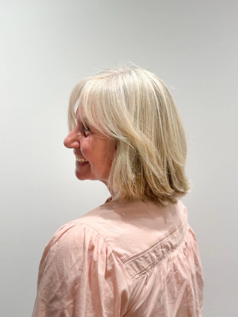 Soft feathered blonde bob with wispy bangs and lightly flipped layers around the shoulders.
