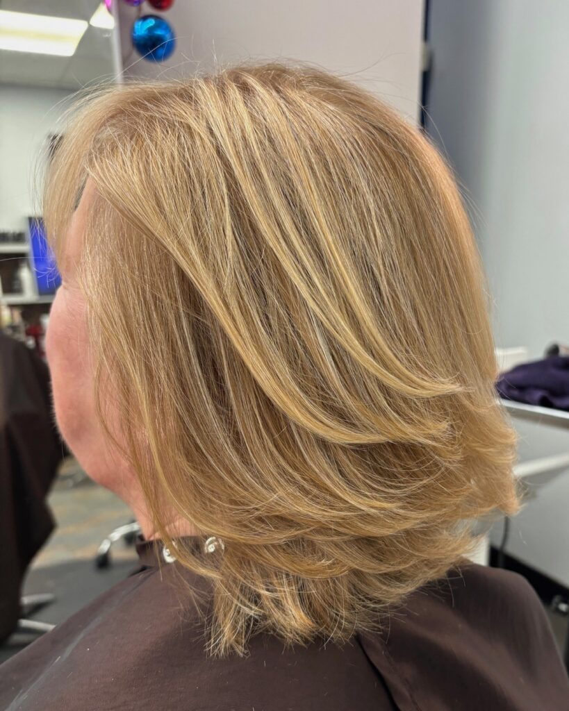 Honey blonde layered bob with feathered flipped-out ends and soft volume.