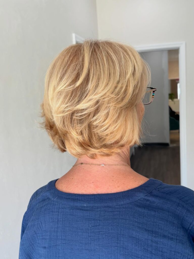 Feathered champagne blonde bob with soft layered volume and a rounded shape.
