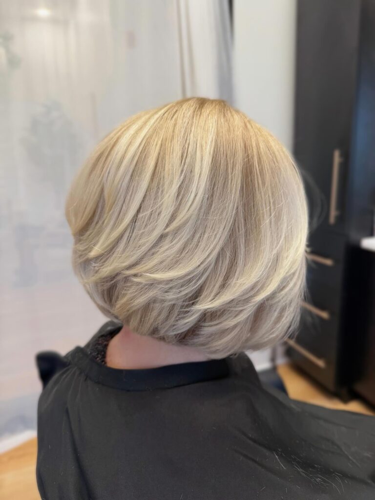 Layered buttery blonde bob with rounded volume and stacked layers in the back.