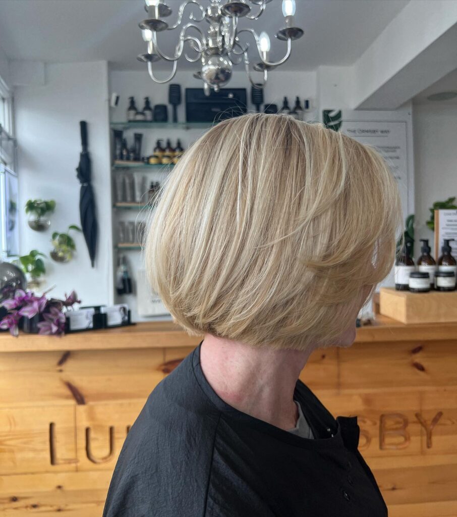 Rounded platinum blonde bob with smooth side-swept layers and tucked-under ends.