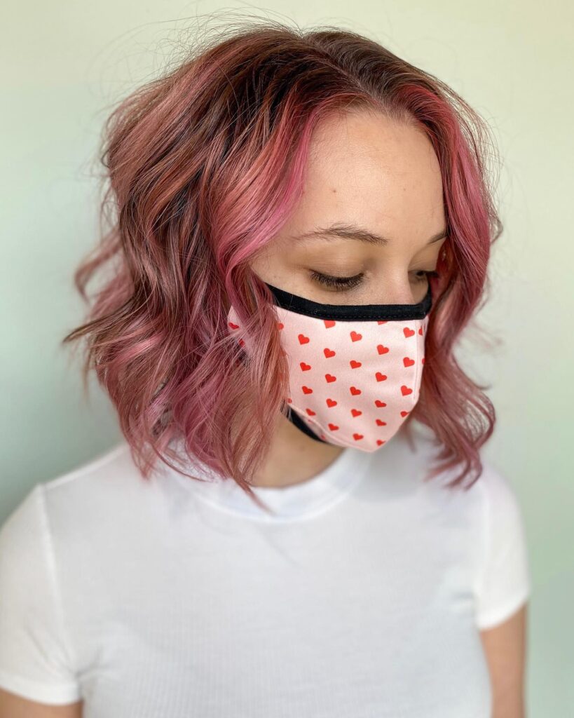 Wavy layered bob with rosy pink highlights and darker mauve roots.