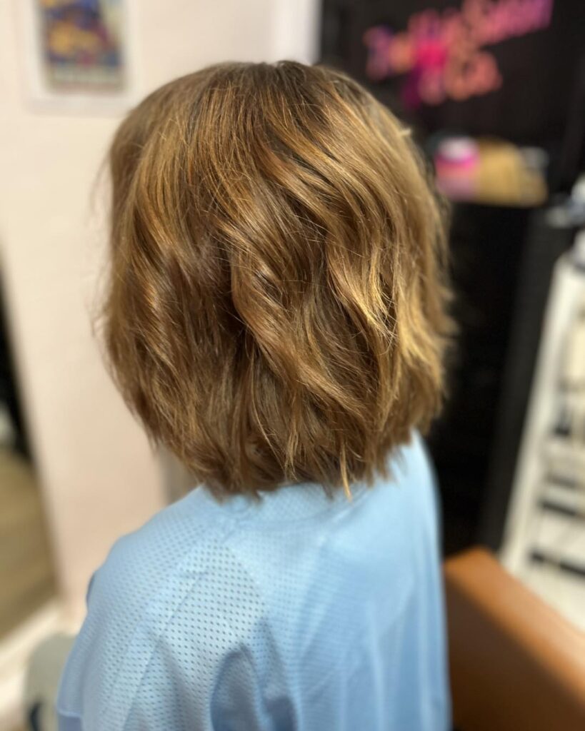 Wavy honey brown bob with golden blonde highlights and soft layered texture.