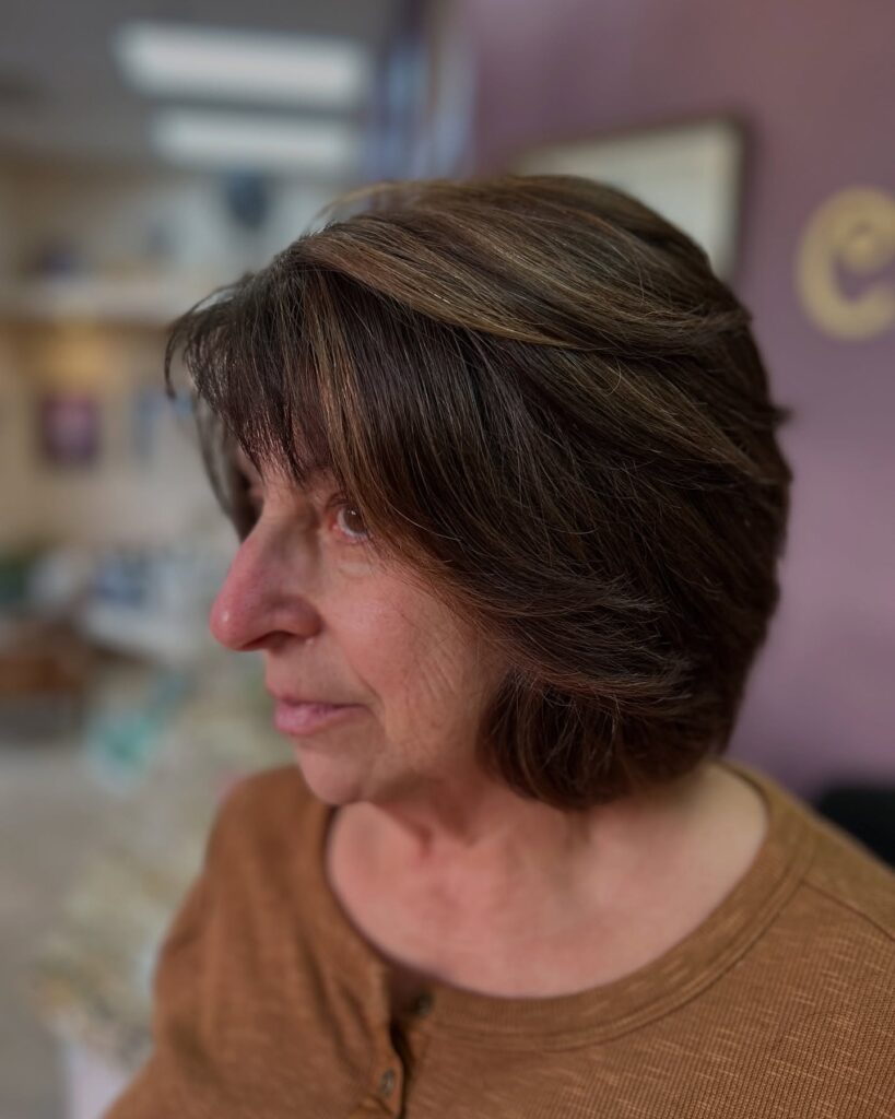Layered brunette bob with feathered ends and soft caramel highlights.