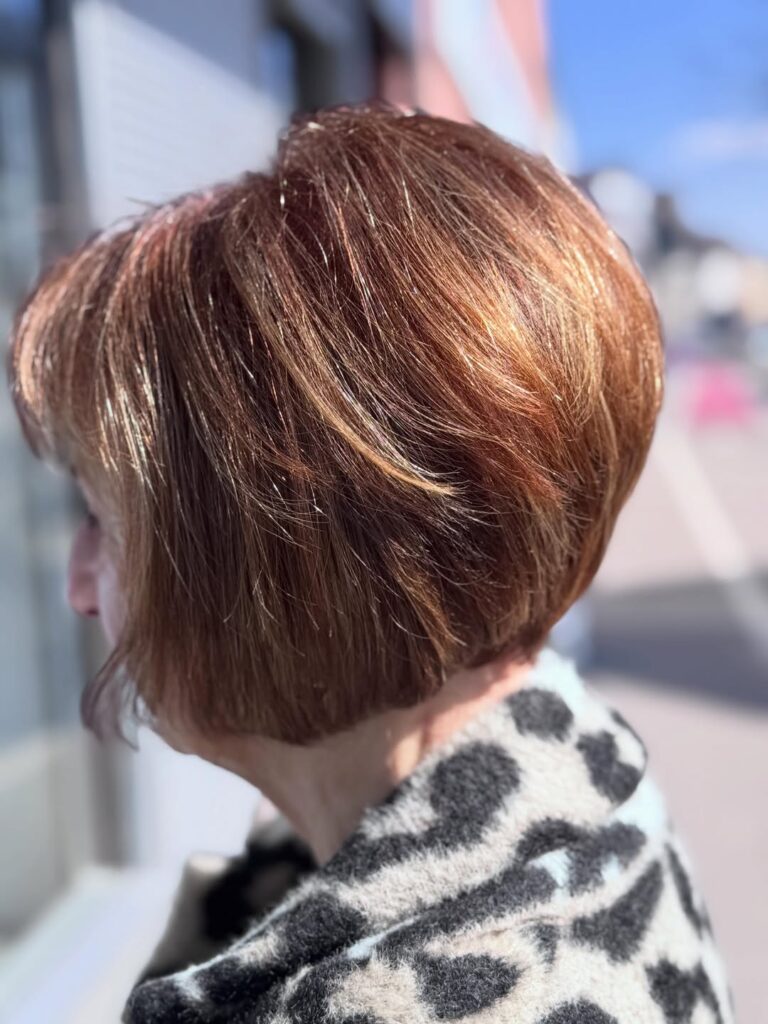 Glossy auburn bob with fine blonde highlights and a softly rounded shape.