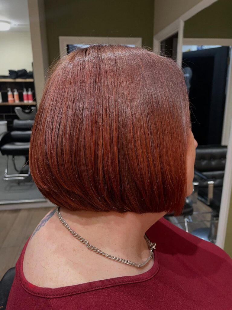 Sleek cherry red bob with subtle bright highlights and a smooth rounded finish.