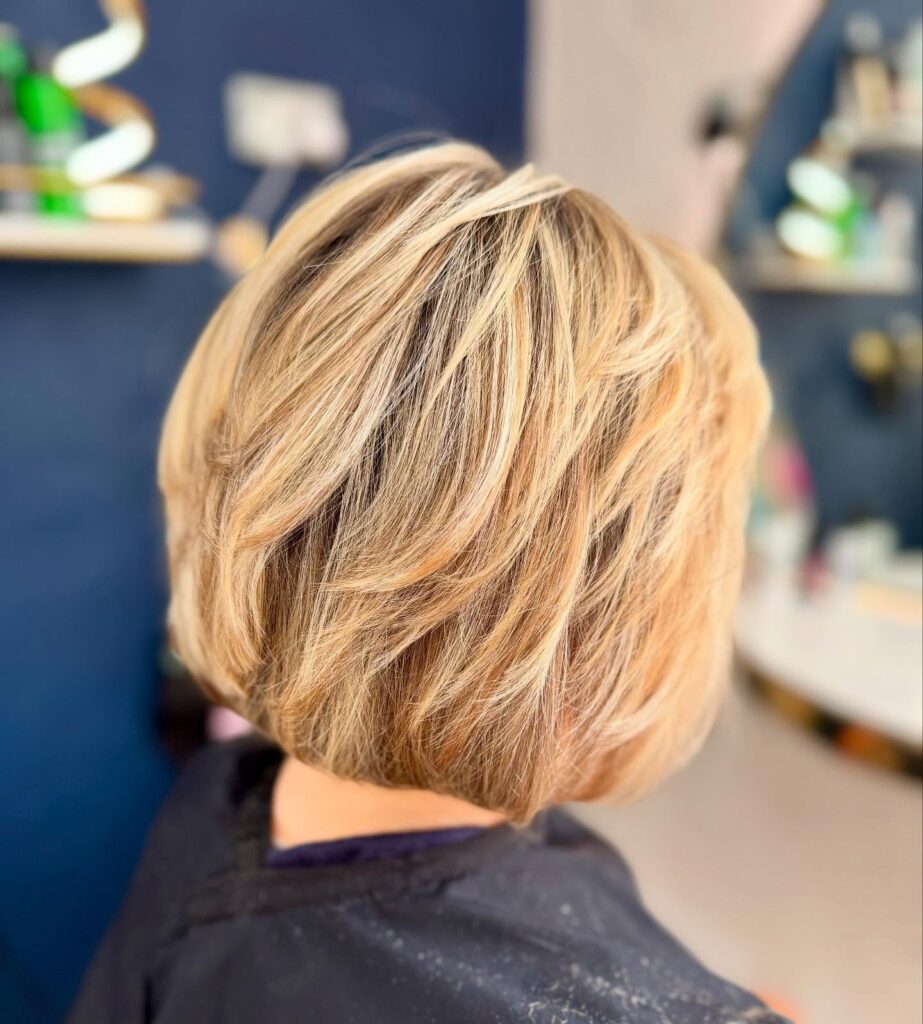 Layered creamy blonde bob with soft beige highlights and a rounded stacked shape.