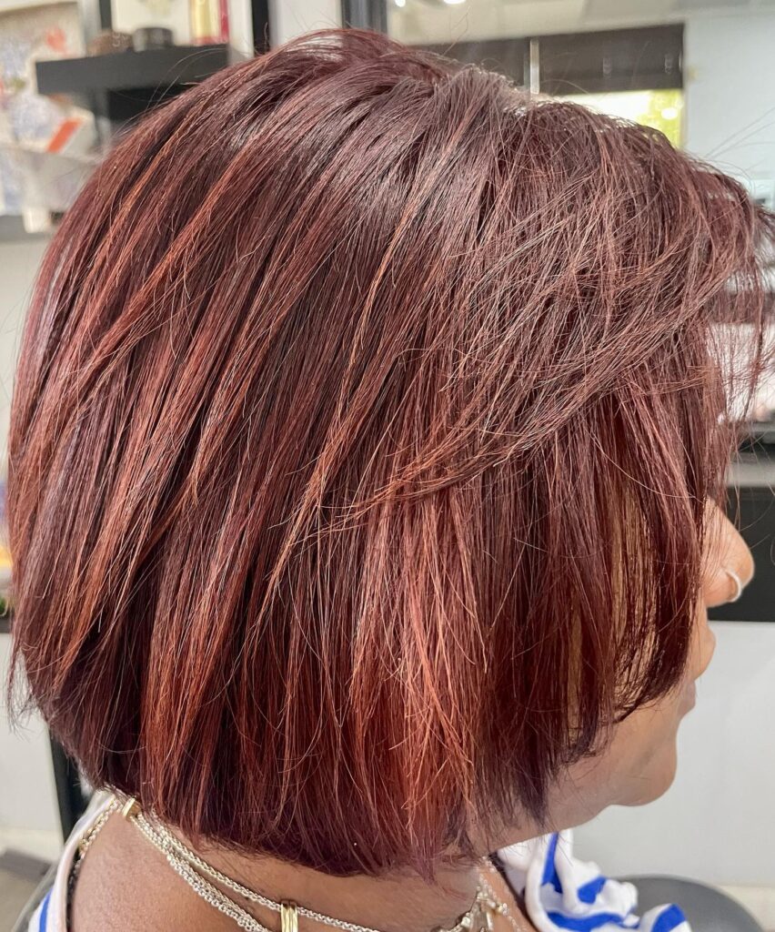 Layered burgundy bob with rosewood highlights and soft textured front layers.