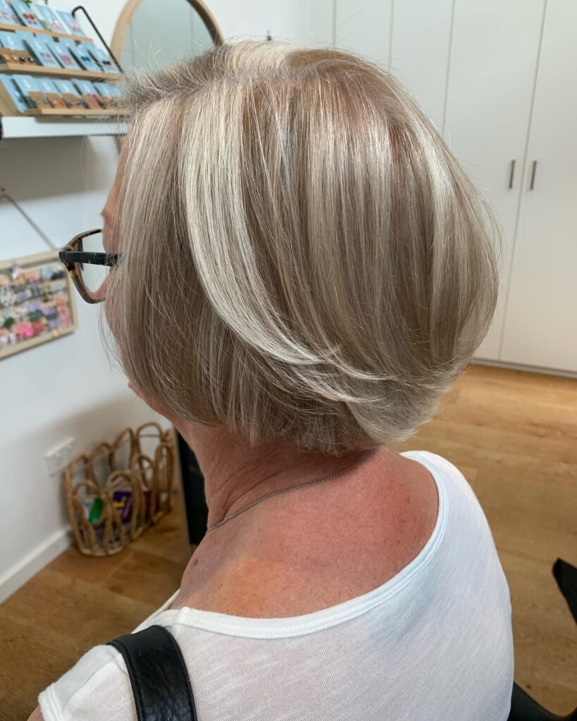 Smooth beige blonde bob with soft layers and bright face-framing highlights.