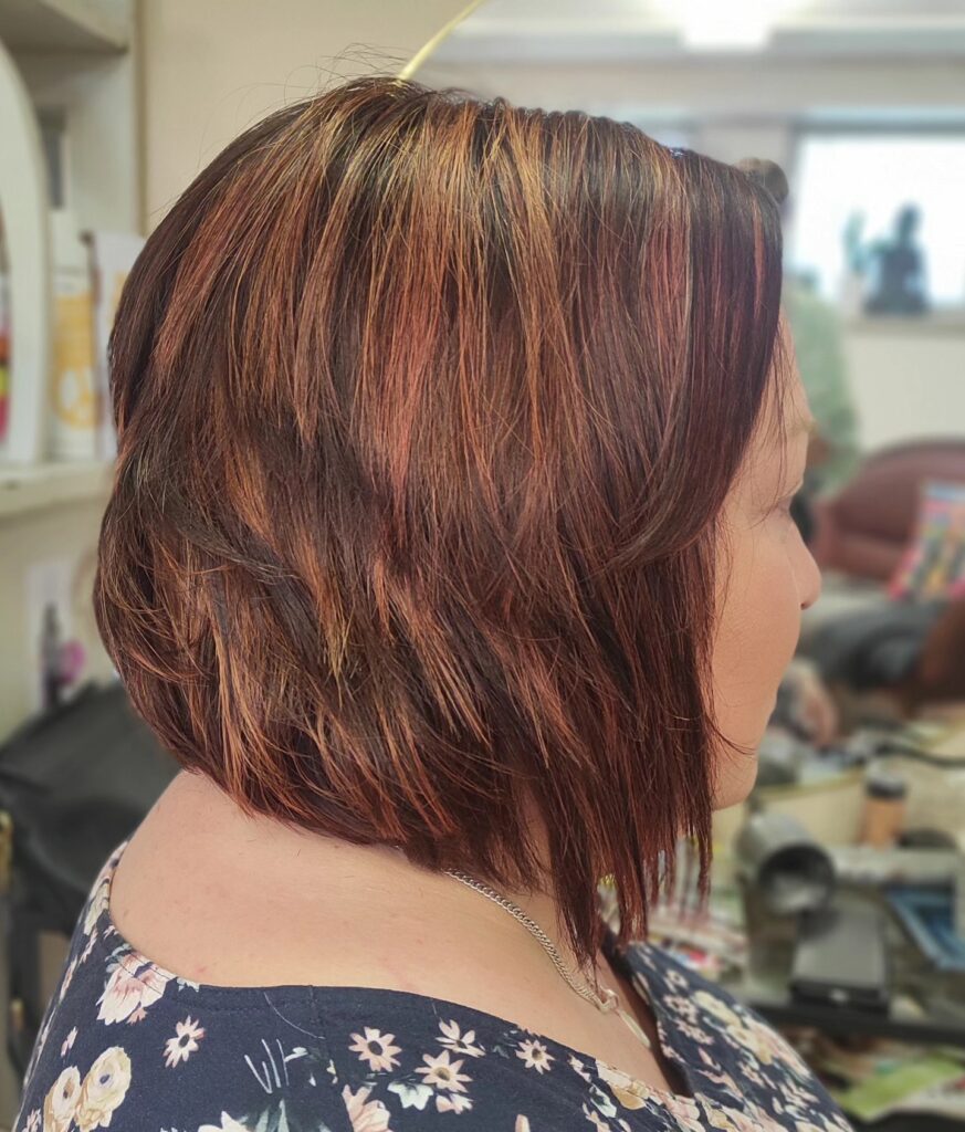 Angled auburn layered bob with copper highlights and soft textured ends.