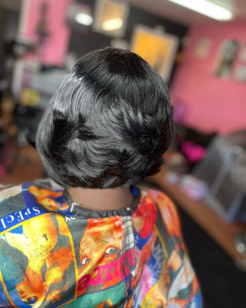 Rounded black bob hairstyle with soft layered waves and a sleek, polished texture.
